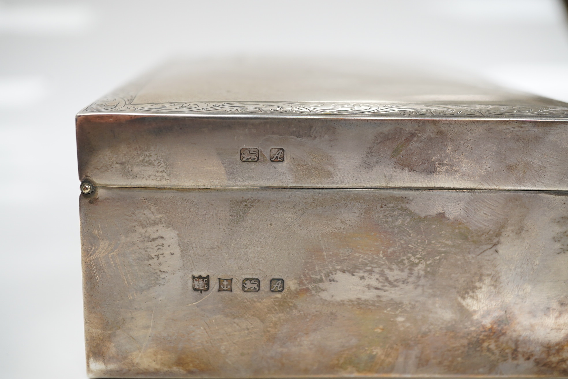 An Elizabeth II silver mounted rectangular cigarette box, with engraved inscription, C.S. Green & Co, Birmingham, 1975, 16.4cm. Condition - poor to fair